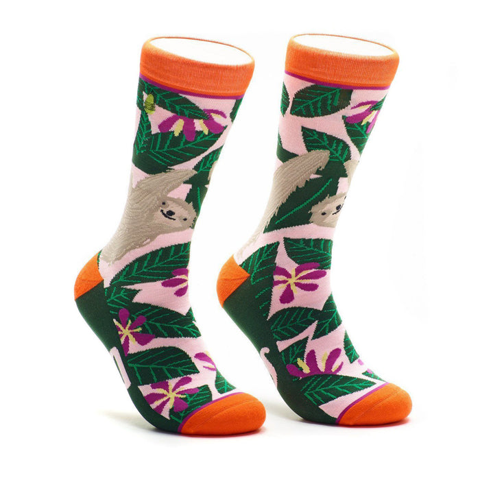 A pair of crew socks with a pink, green, and orange design. The socks feature sloths hanging from tropical leaves and flowers. }}