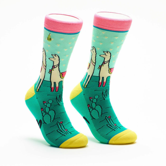 Crew socks in teal, pink, and yellow. Llamas wearing flower crowns stand in a cactus landscape on a pastel blue background. }}