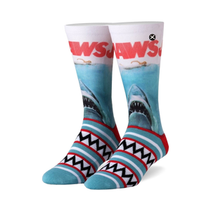 Pair of Jaws crew socks.  White and teal stripes at the bottom, featuring the Jaws movie poster with a great white shark on the main body of the sock.