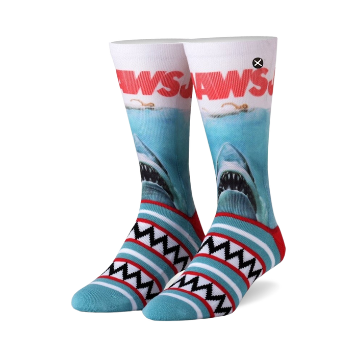 Pair of Jaws crew socks.  White and teal stripes at the bottom, featuring the Jaws movie poster with a great white shark on the main body of the sock.