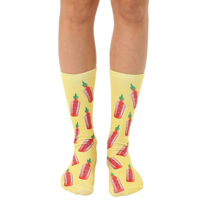 Crew socks in yellow with a repeating pattern of red and green hot sauce bottles. Fun and quirky design.