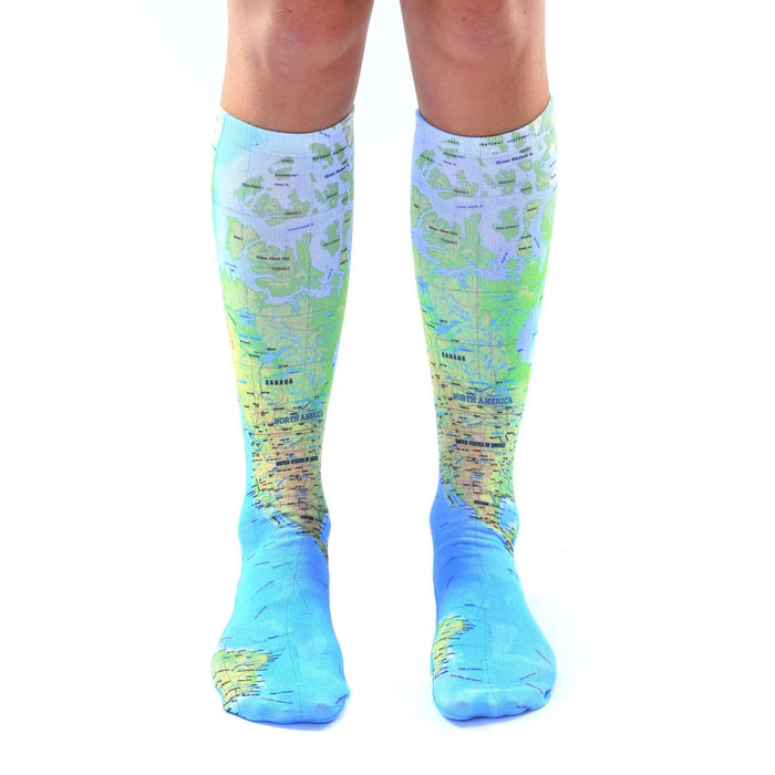 Pair of light blue knee-high socks with a detailed world map design.  The map features green and brown landmasses and blue oceans.