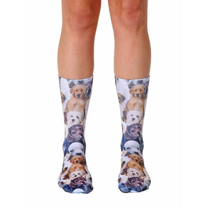 A pair of crew socks covered in an all-over print of adorable puppies in various breeds and colors. The socks are mainly white with brown, tan, and black puppies.