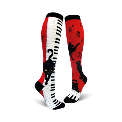 A pair of red and white knee-high socks with a piano keyboard and playful black cats. Musical notes are also featured.