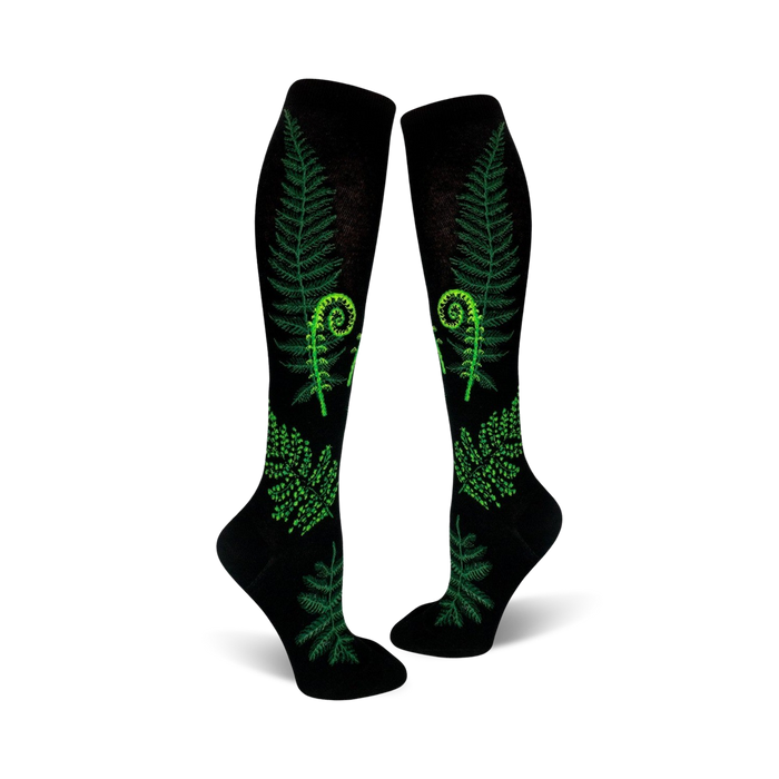 Pair of black knee-high socks featuring bright green ferns and fiddleheads. Botanical print on a black background. }}