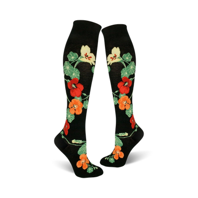 Pair of black knee-high socks with a pattern of orange, red, and yellow nasturtium flowers and green leaves.