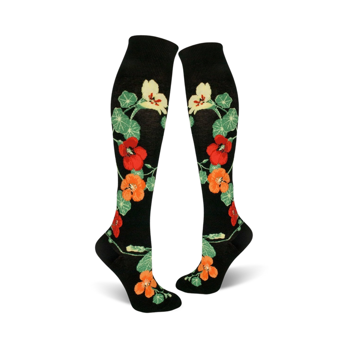 Pair of black knee-high socks with a pattern of orange, red, and yellow nasturtium flowers and green leaves.