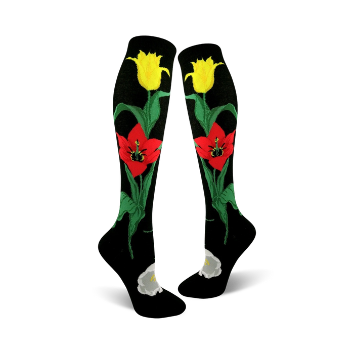 Pair of black knee-high socks with red and yellow tulips and green stems. A white flower is at the ankle. }}