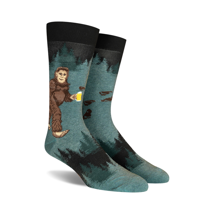 A person is wearing a pair of green socks with a pattern of bigfoot holding a beer on them. The socks are pulled up over the person's blue jeans.