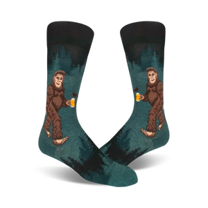 Pair of teal crew socks depicting a Bigfoot character enjoying a beer in a forest setting. Darker teal and black accents.