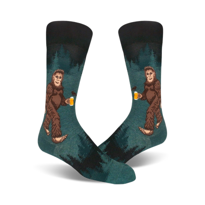 Pair of teal crew socks depicting a Bigfoot character enjoying a beer in a forest setting. Darker teal and black accents.
