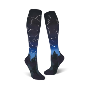 Pair of dark blue and black knee-high socks with constellations and a forest silhouette design.
