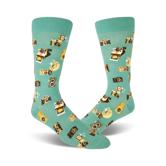Pair of teal crew socks with a whimsical pattern of retro cameras and flashes in yellow and brown. Fun and quirky style. }}