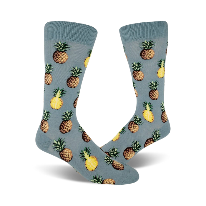 Close up view of a pair of blue crew socks with a repeated pineapple pattern. Pineapples are yellow and brown.