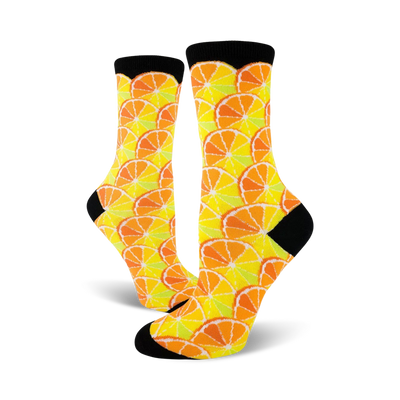 Pair of crew socks with a citrus fruit pattern. Oranges and lemons in yellow, orange, and pale green on a white background. Black cuffs.