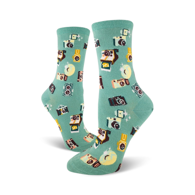 A pair of teal crew socks adorned with a whimsical pattern of retro cameras, film canisters, and sparkling details.