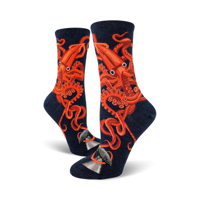 A pair of women's crew socks in navy blue, adorned with a striking orange squid design. The squid's tentacles wrap around a small grey whale illustration at the bottom.