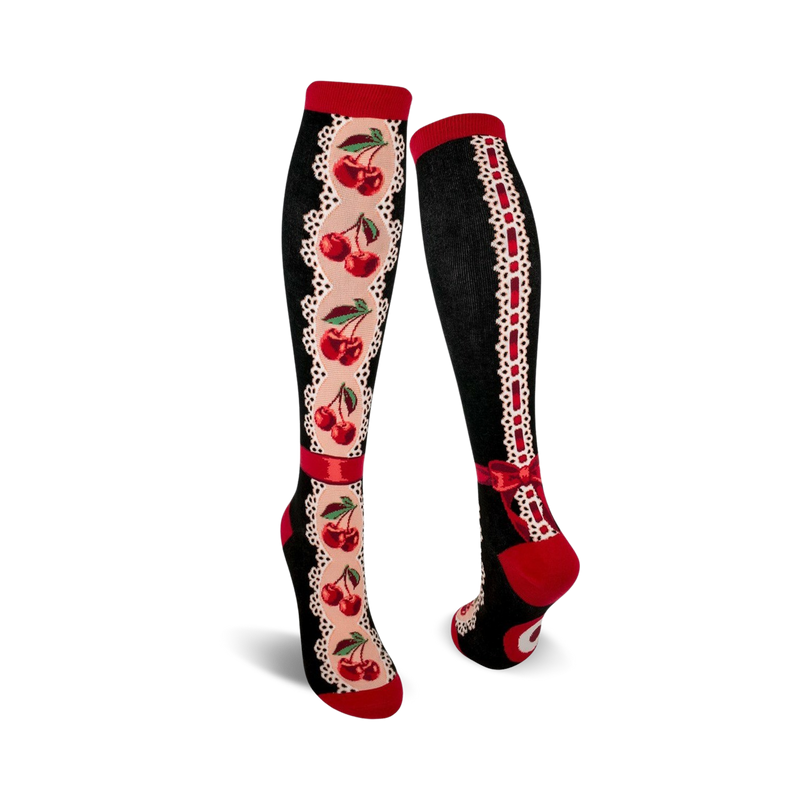 Pair of women's knee-high socks. Black background, red cherries, cream lace accents, and red ribbon bow detail.