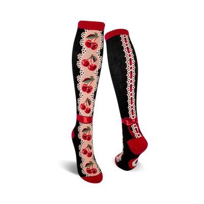 Pair of women's knee-high socks. Black background, red cherries, cream lace accents, and red ribbon bow detail.