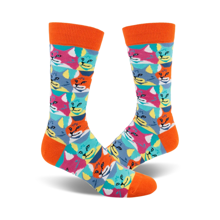 A pair of crew socks with an orange cuff. The socks feature a repeating pattern of colorful cat faces in a Pop Art style. }}