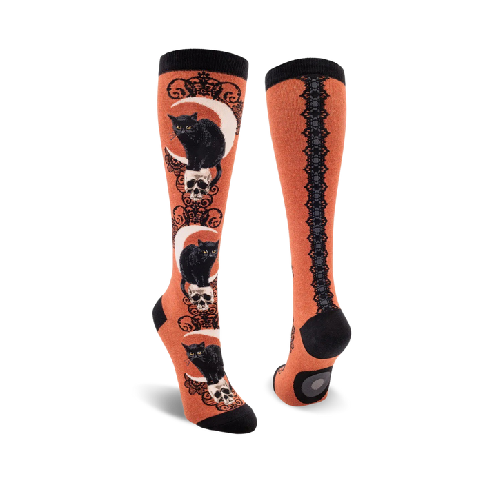 Pair of knee-high socks; orange and black, purple and black. Design features black cats sitting on skulls beneath crescent moons.