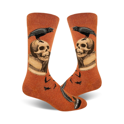 Pair of burnt orange crew socks. A black raven perches on a skull resting on an open book, with a quill pen at the bottom. Small ravens also in the background.