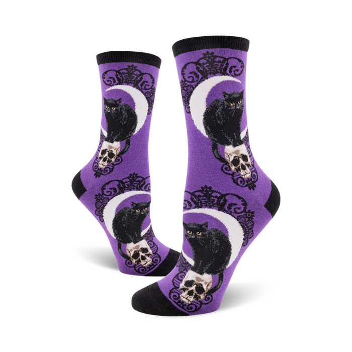 purple crew socks for women with a pattern of black cats sitting on skulls and crescent moons behind them.   