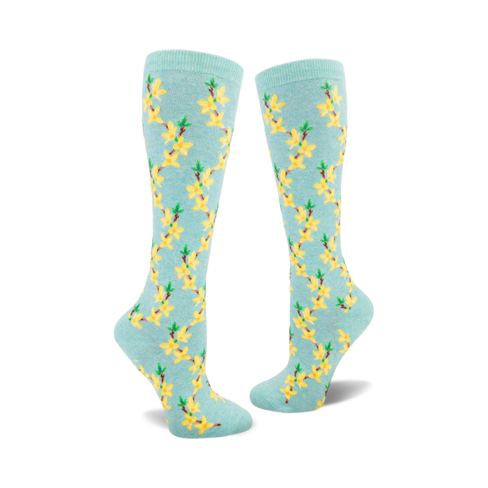 Pair of women's knee-high socks in pastel blue with a repeating pattern of yellow forsythia flowers and green stems. }}