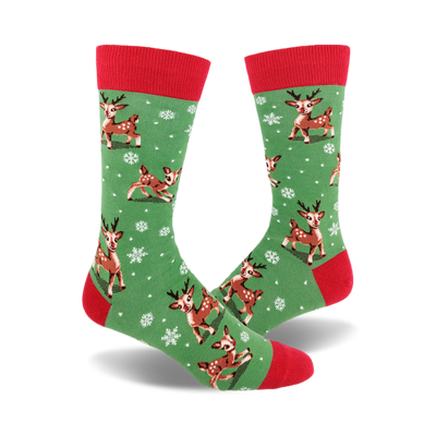 A pair of crew socks with a green background, red cuffs, and a pattern of brown reindeer and white snowflakes.