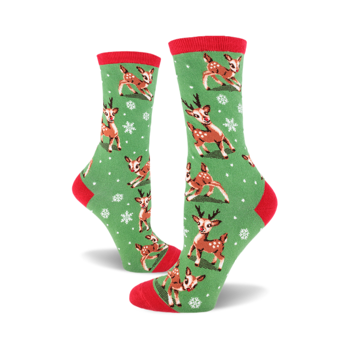 A pair of women's crew socks in green with a red cuff. The socks feature a pattern of cute reindeer and snowflakes. }}