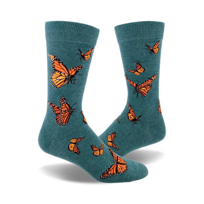 A pair of teal crew socks featuring a pattern of orange monarch butterflies.  A whimsical and nature-inspired design. }}