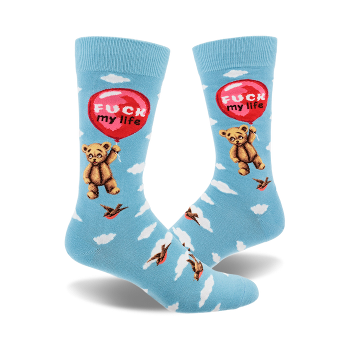 a pair of blue socks with a pattern of white clouds, black birds, and a brown teddy bear holding a red balloon with the words 'fuck my life' on it. }}