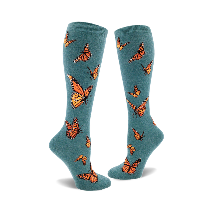 the teal blue socks have a pattern of orange monarch butterflies with black and white details. }}