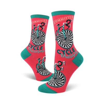 Crew socks in coral with teal cuffs. The design features a black and white hypnotic bicycle wheel and the words 'Cycle Therapy'.