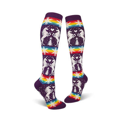 Pair of purple knee-high socks with a whimsical design featuring white unicorns, snowflakes, rainbow stripes, and small pine trees.
