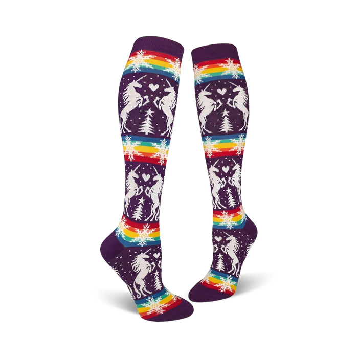 Pair of purple knee-high socks with a whimsical design featuring white unicorns, snowflakes, rainbow stripes, and small pine trees. }}