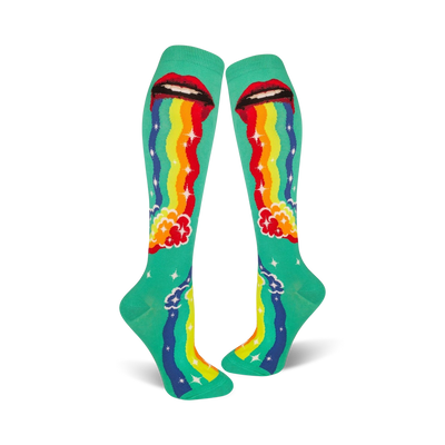 A pair of teal knee-high socks with a whimsical design. Red lips 'puke' a rainbow onto teal clouds and stars.