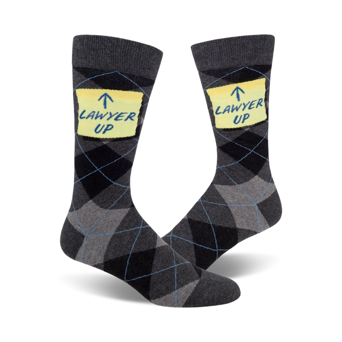 Pair of men's crew socks in grey and black argyle pattern. Each sock features a yellow sticky note with the phrase 'Lawyer Up' written on it. }}