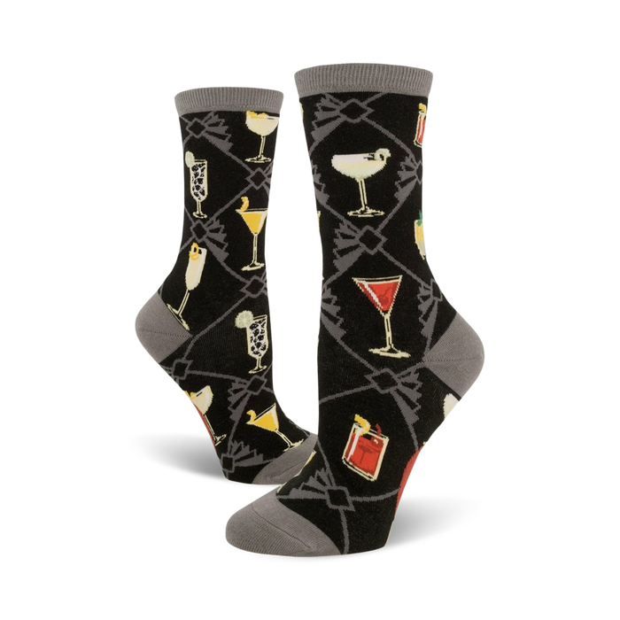 A pair of women's crew socks in black with a gray cuff. The socks feature a pattern of colorful cocktail illustrations set against a dark background. }}