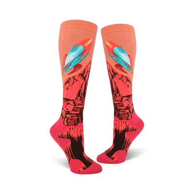 Pair of coral knee-high socks with a rocket launching from a rocky planet design. Features teal, orange, and black details.