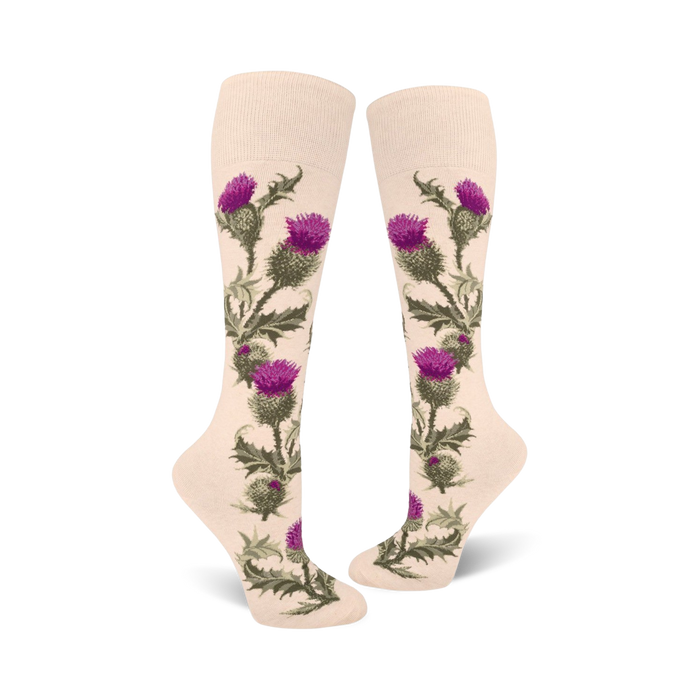 Pair of cream knee-high socks adorned with a vertical pattern of purple thistles and green leaves. }}