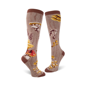 Pair of knee-high socks in brown and beige, featuring a whimsical illustration of various mushrooms and a wood-grain pattern.