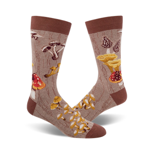 Pair of crew socks with a mushroom design.  The socks are beige/brown and green with various colorful mushroom illustrations on a wood-grain background.