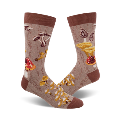 Pair of crew socks with a mushroom design. The socks are beige/brown and green with various colorful mushroom illustrations on a wood-grain background.