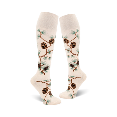 Pair of off-white knee-high socks with brown pine cones and green pine branches artfully arranged on the fabric.