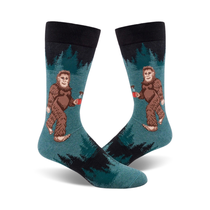 crew length socks in dark blue and teal feature cartoonish sasquatch holding coffee mugs surrounded by pine trees.   }}