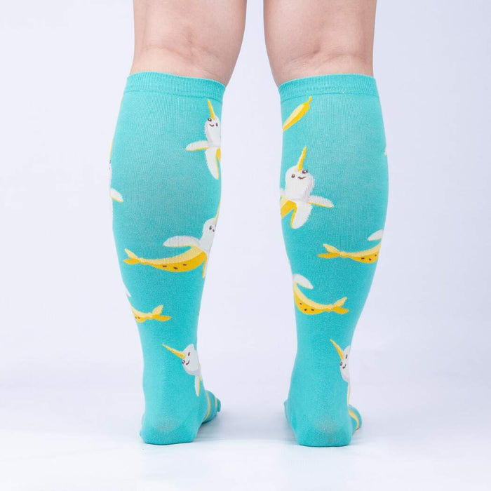 A pair of blue knee-high socks with a pattern of yellow bananas with narwhal faces.