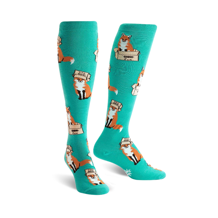 Pair of teal knee-high socks with a playful pattern of orange foxes wearing boxes on their heads.  }}