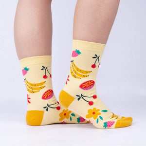 A pair of yellow socks with a pattern of bananas, strawberries, and flowers.