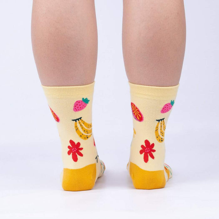 A pair of yellow socks with a pattern of bananas, strawberries, and flowers.